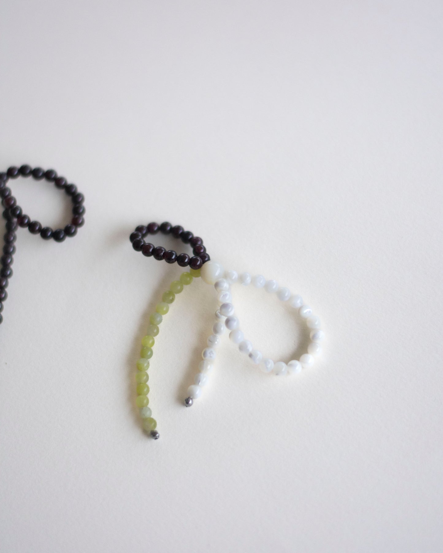 detail of an earring made in mother of pearl, garnet and lemon jasper, featuring a bow form.