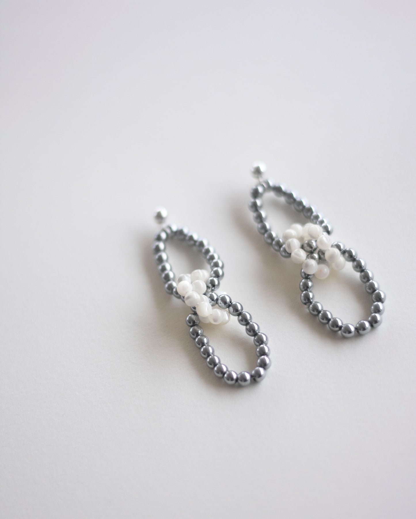 Pair of pearl and silver hematite beaded earrings on a light gray background, handmade, ethically