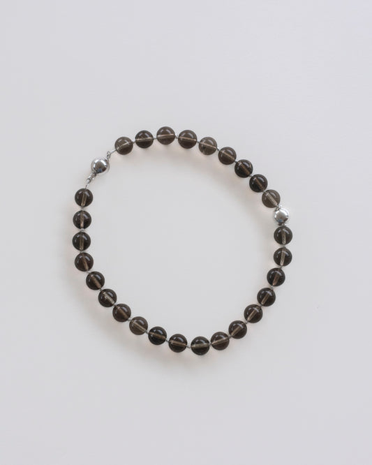 Smoky quartz beaded necklace, hand-knotted on off-white silk thread, laid flat on a white background