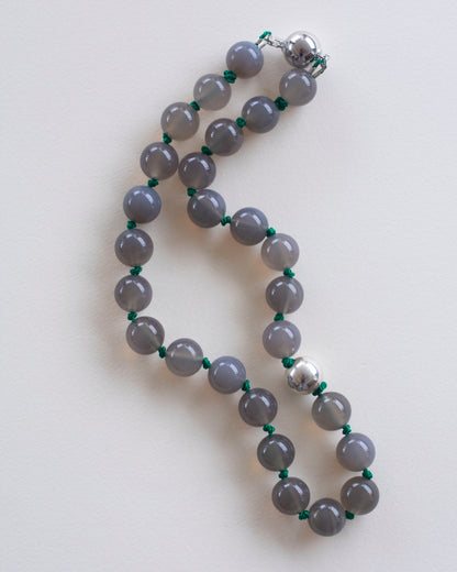 Gray agate beaded necklace with silver clasp on a white background and handknotted on emerald green silk thread