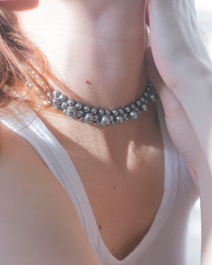 Close-up of a person wearing a silver hematite double-layered beaded necklace with a blurred background