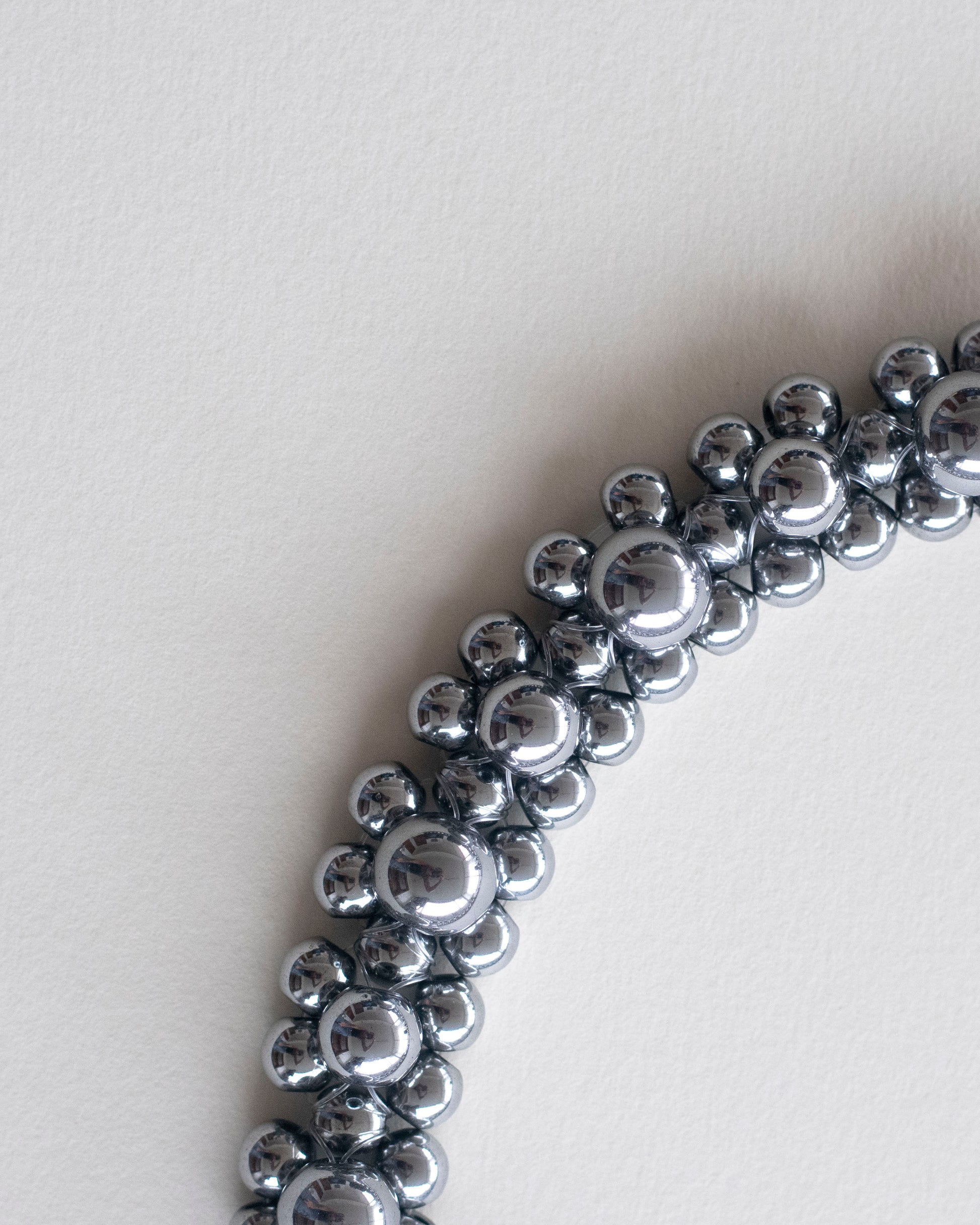 close up of silver hematite beaded choker necklace, on a light gray background