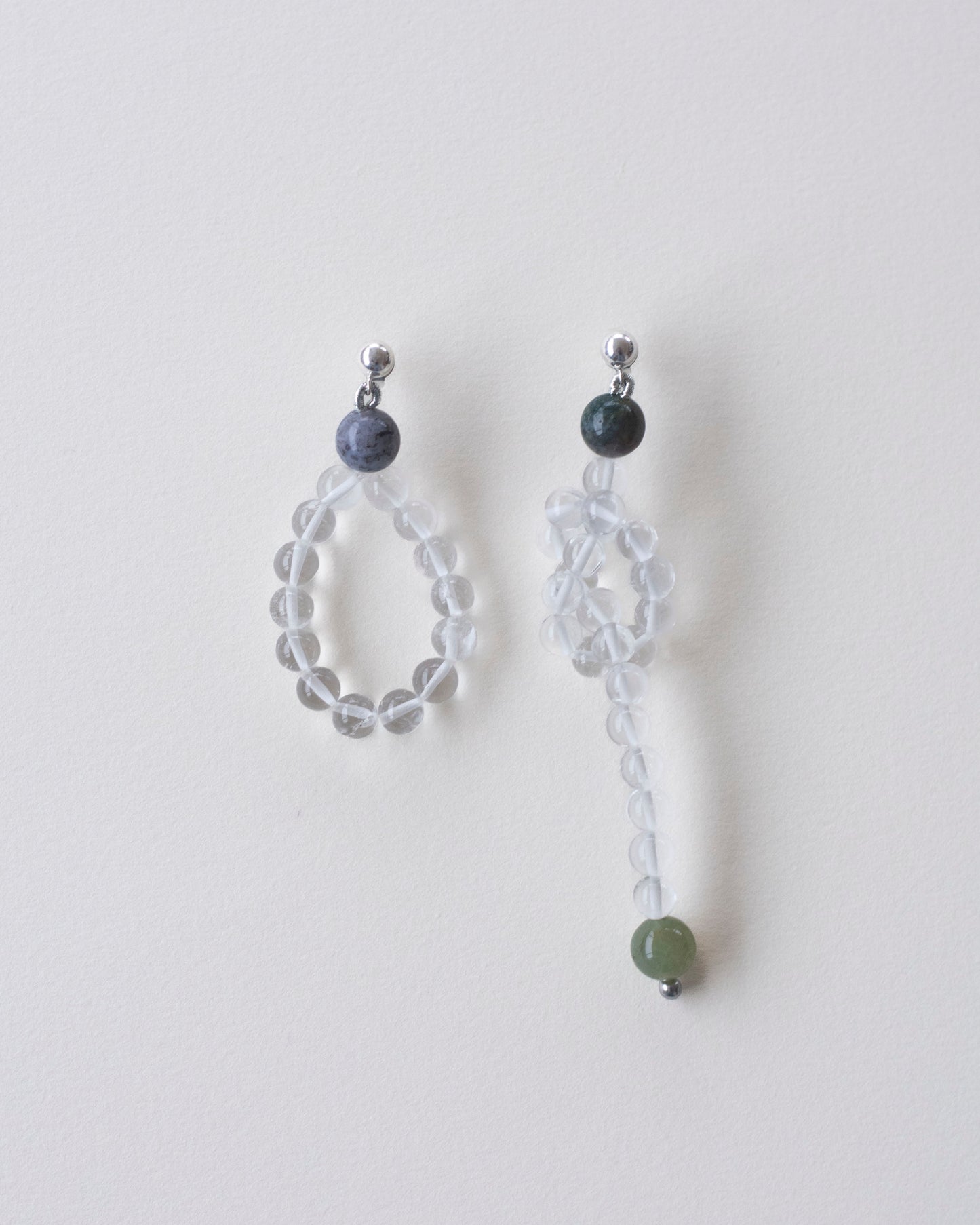 Pair of beaded earrings made in crystal quartz and indian agate on a light gray background