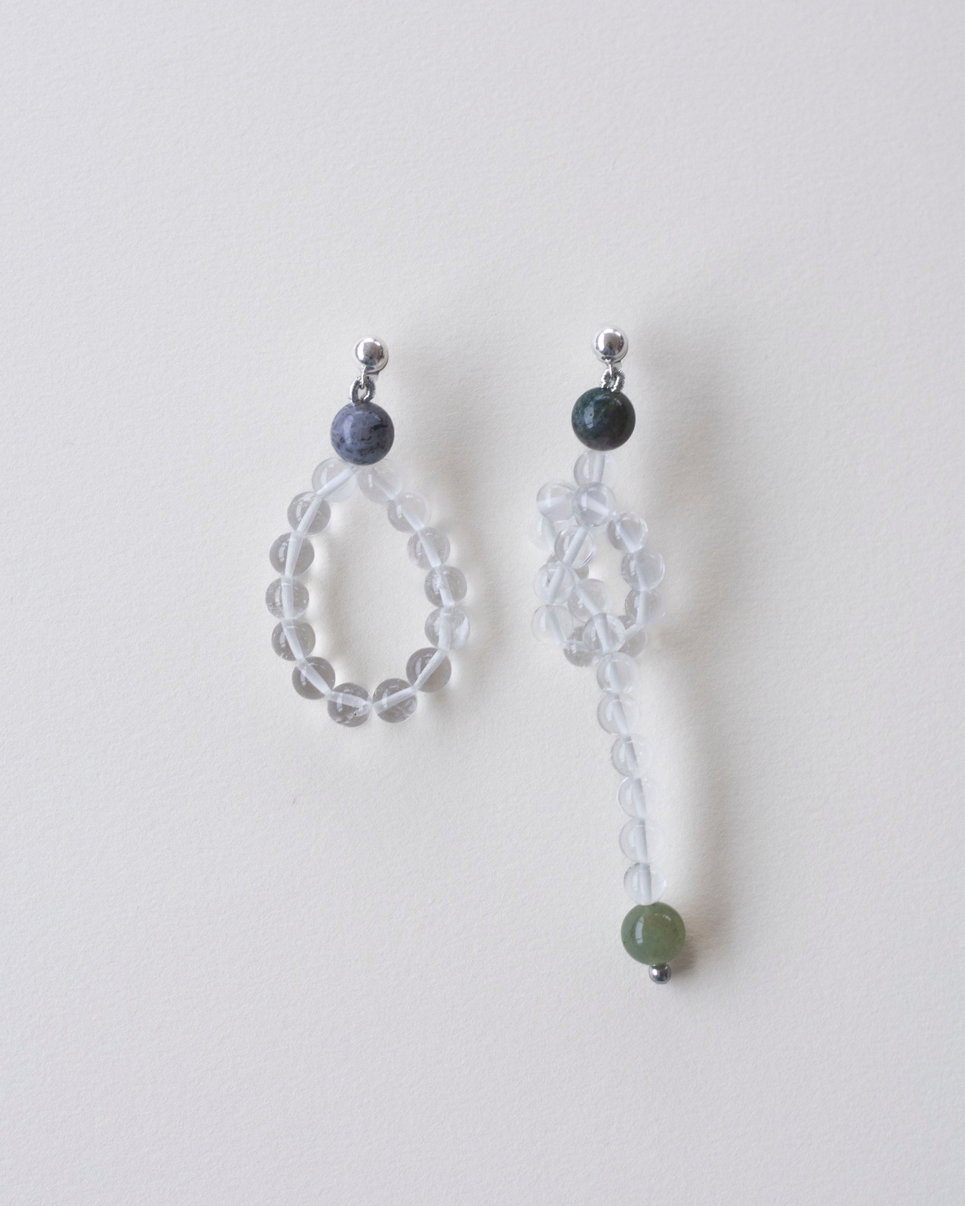 Pair of beaded earrings made in crystal quartz and indian agate on a light gray background