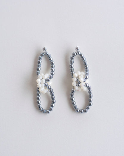 Pair of beaded earrings in hematite and mother of pearl on a light gray background