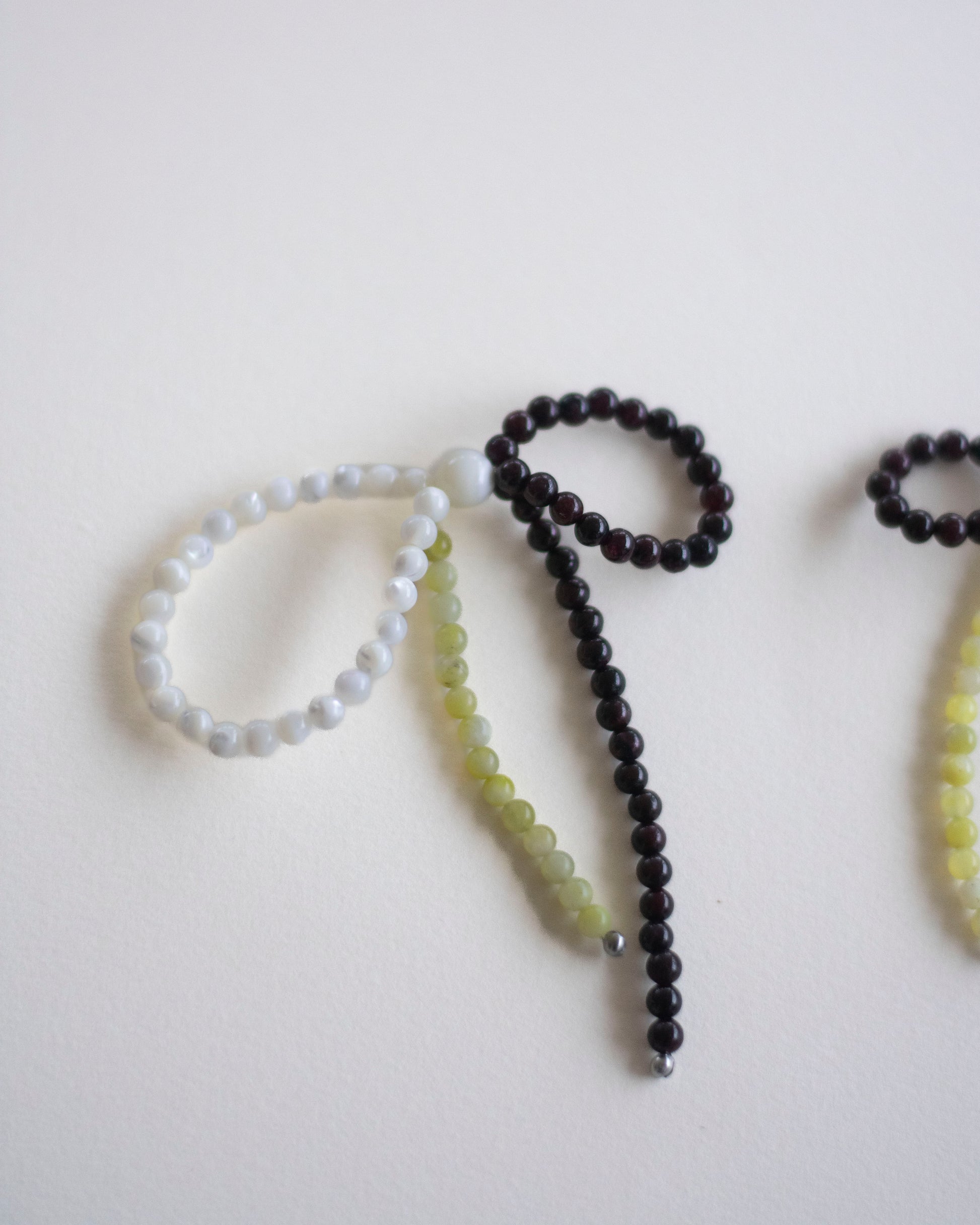 detail of an earring made in mother of pearl, garnet and lemon jasper, featuring a bow form.
