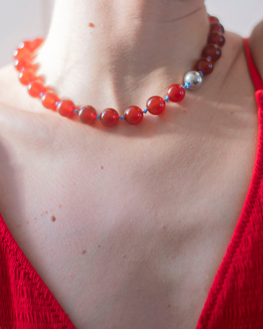 Person wearing a red carnelian beaded necklace with a 925 sterling silver bead