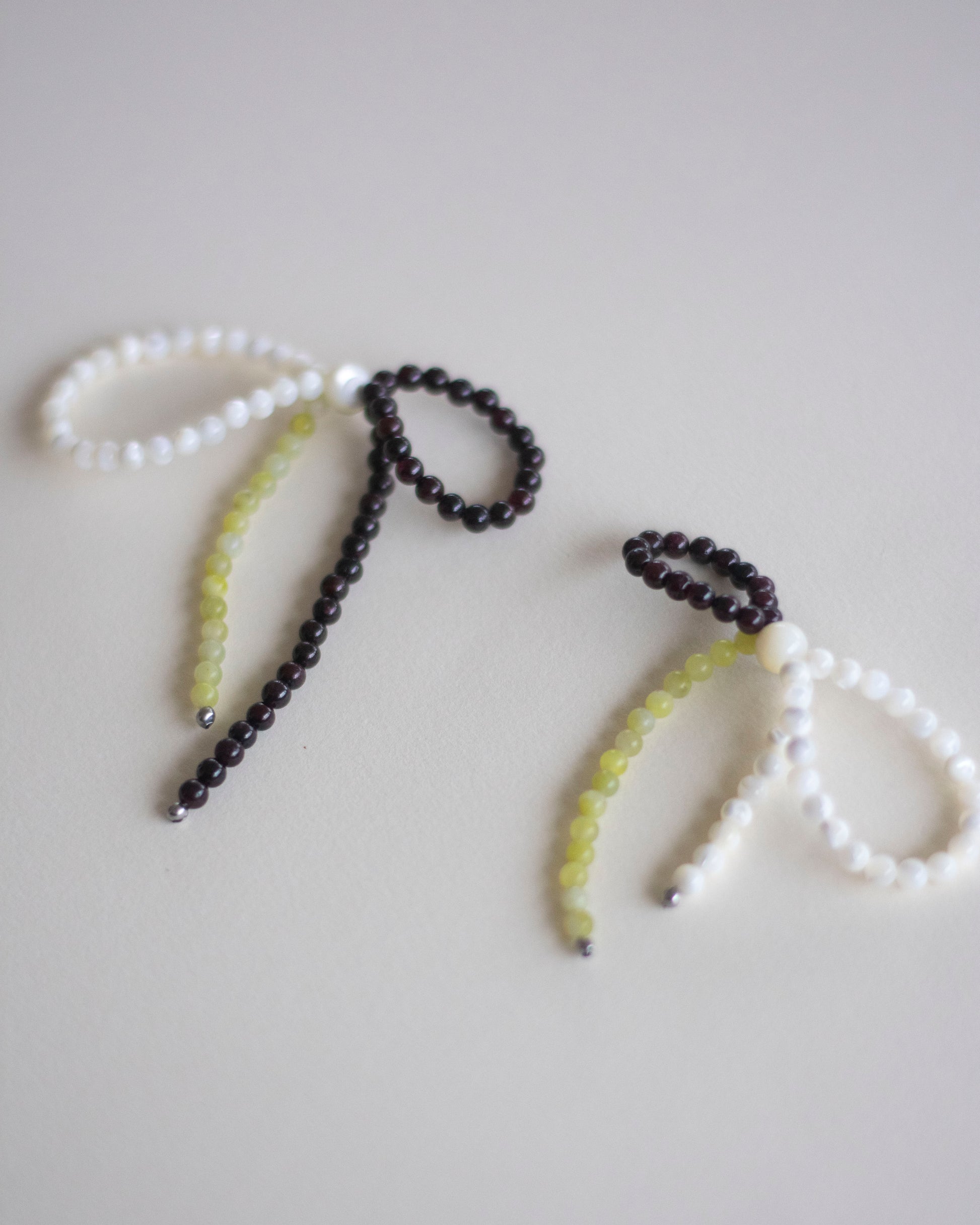 a pair of mother of pearl, garnet and lemon jasper beaded earrings, handmade in a bow form.