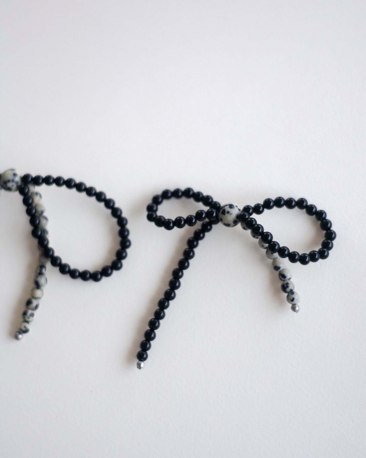 Black onyx and dalmatian jasper beaded earring bow on a white background