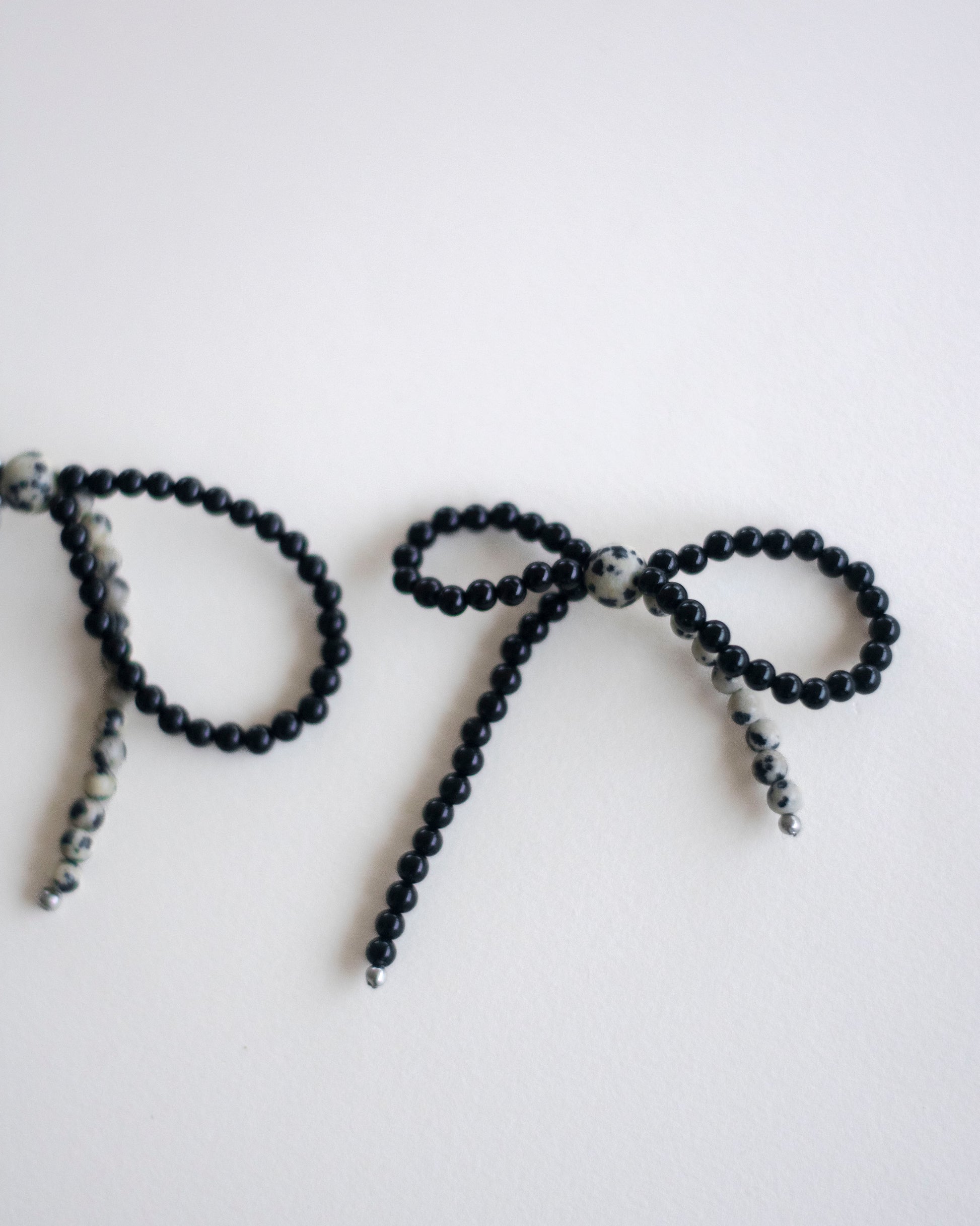 Black onyx and dalmatian jasper beaded earring bow on a white background