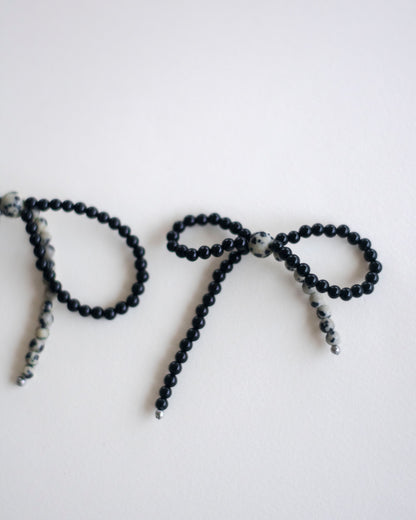 Black onyx and dalmatian jasper beaded earring bow on a white background