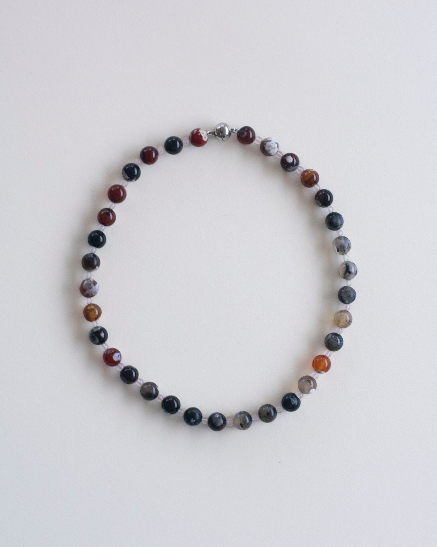 fire lace agate and rose quartz beaded necklace on a light gray background