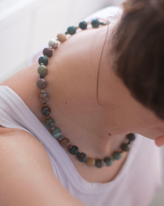 Person wearing a beaded indian agate necklace with a blurred background