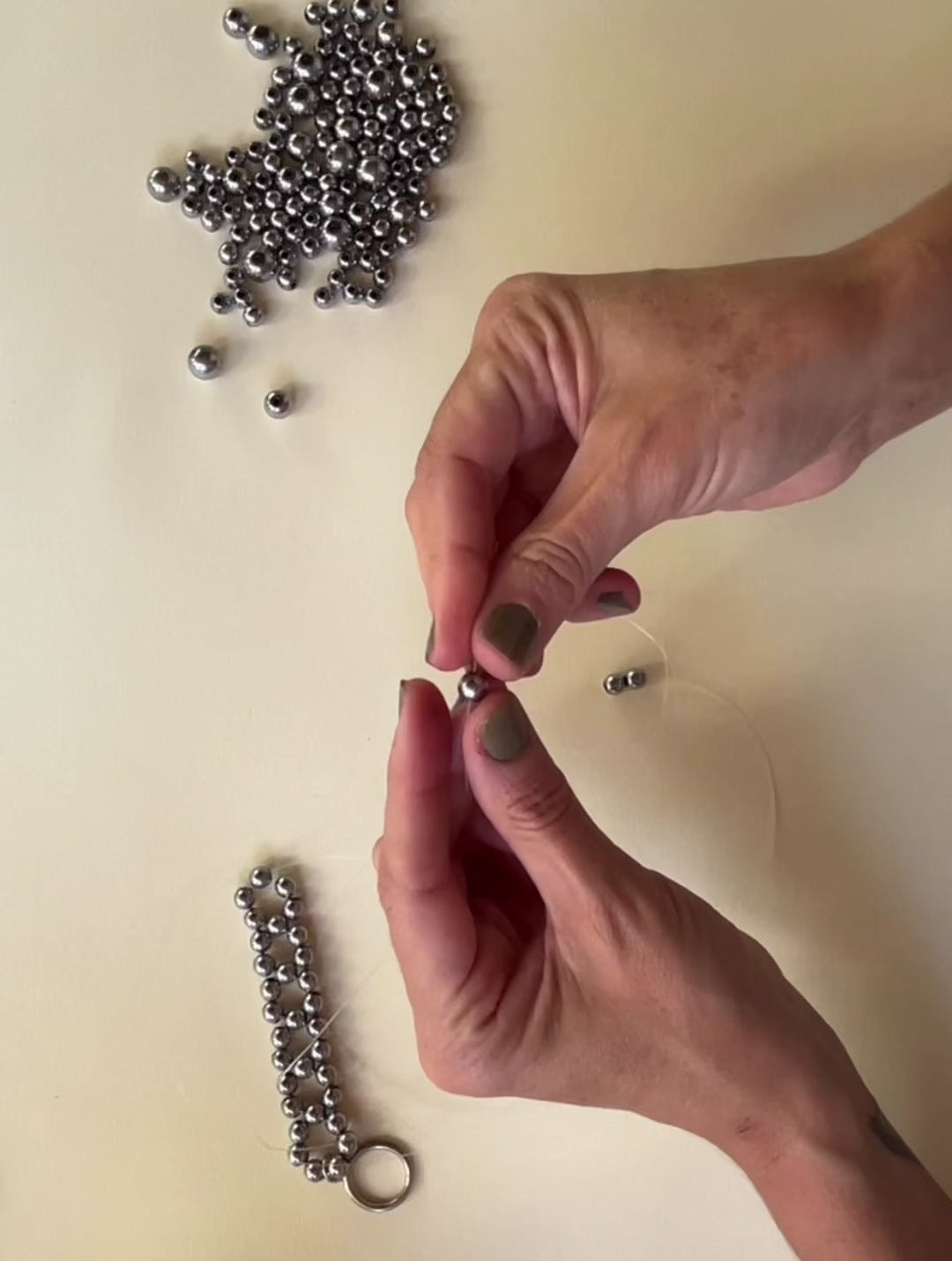 Load video: hands weaving and crafting a hematite beaded necklace